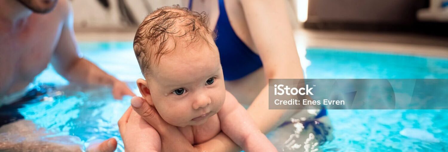 Parent swimming with baby in pool during holiday