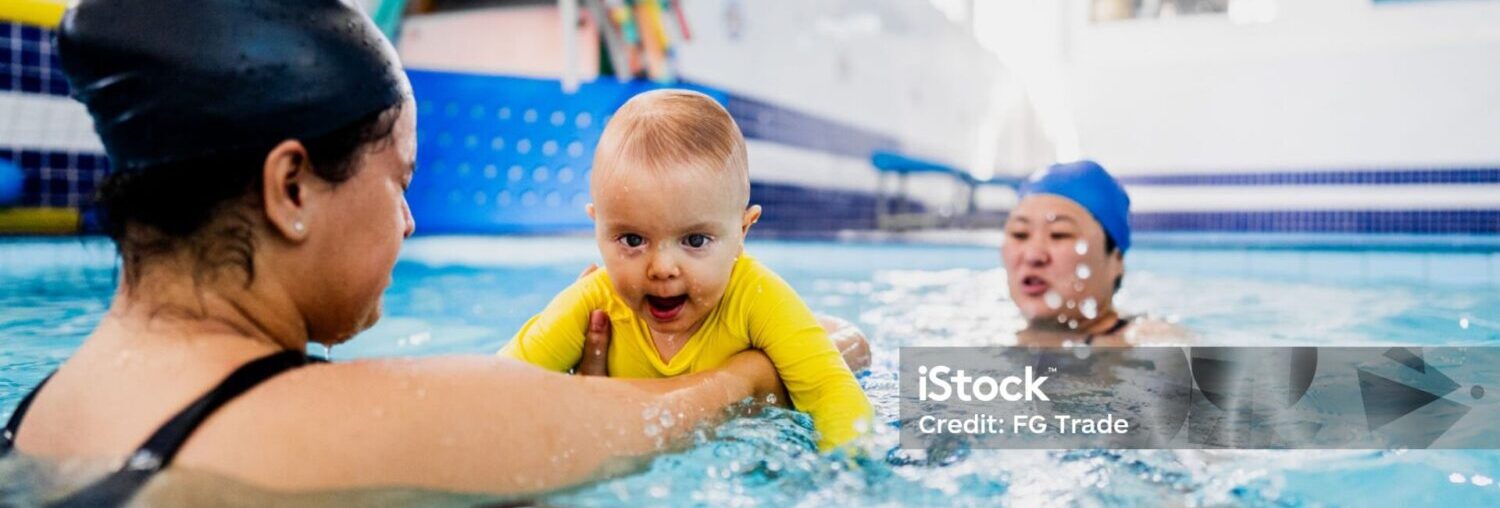 Mother playing with son during swimming pool lessons